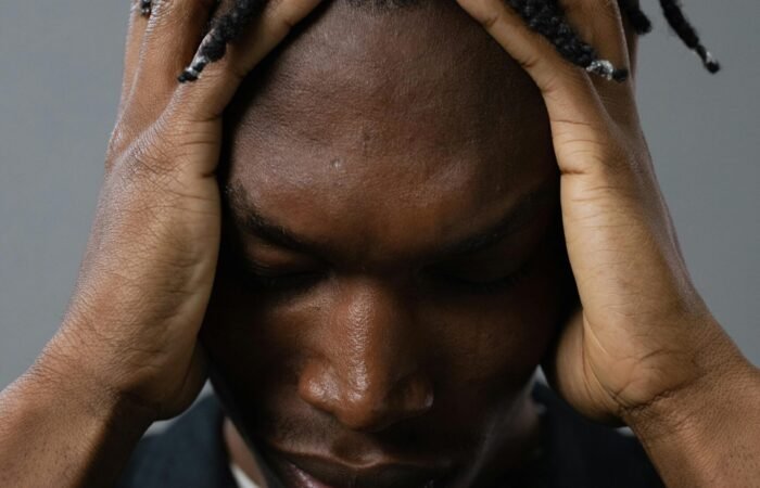 رجل يمسك رأسه بتوتر يعكس ارتباط العقل بالجسد وتأثير الضغط النفسي على الألم الجسدي